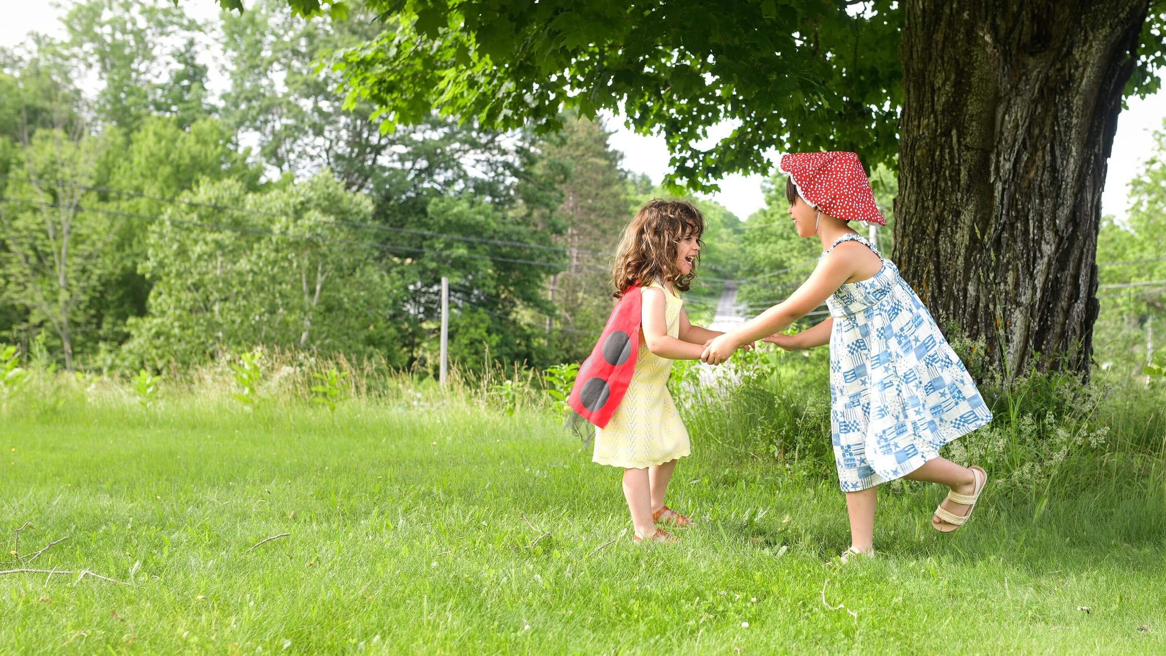 Two girls playing in yard with a tree in the background.