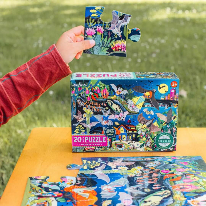 A child holds up large puzzle piece to the 20 pc Cauldron of Bats puzzle from eeBoo.