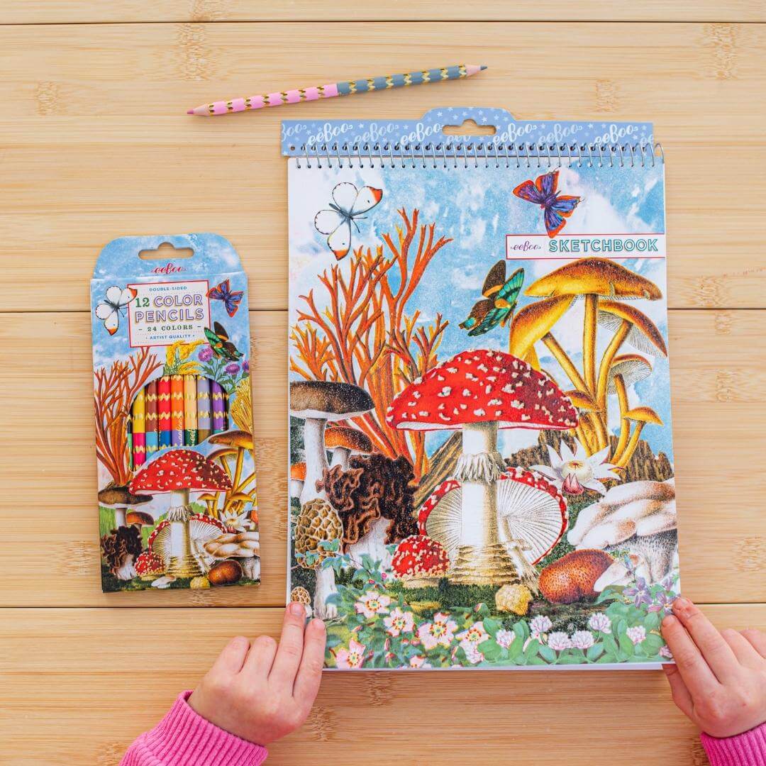 eeBoo sketchbook with mushroom design on a wooden surface, accompanied by matching color pencils.