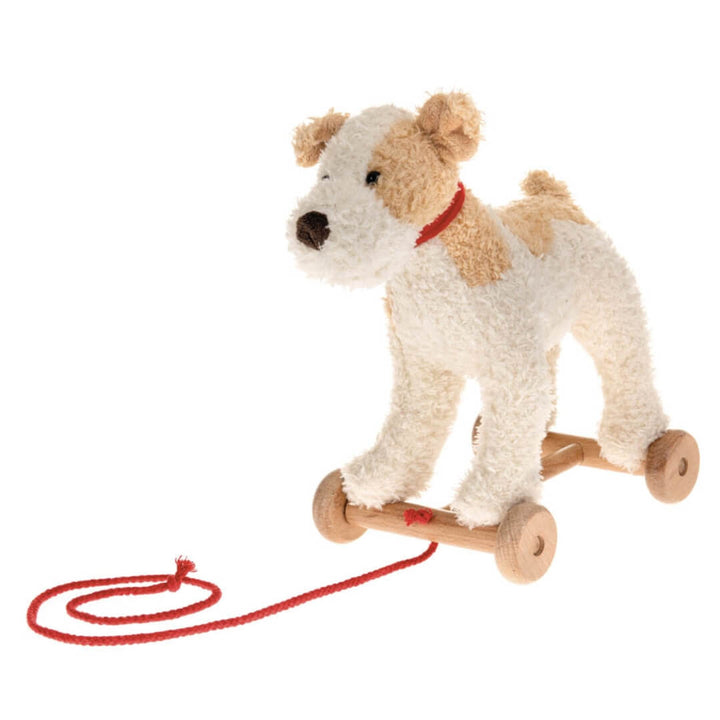 Soft plush Eliot Dog pull-along toy with a red cord and sturdy wooden wheels, designed for toddlers to push or pull during active play shown  against a white background.