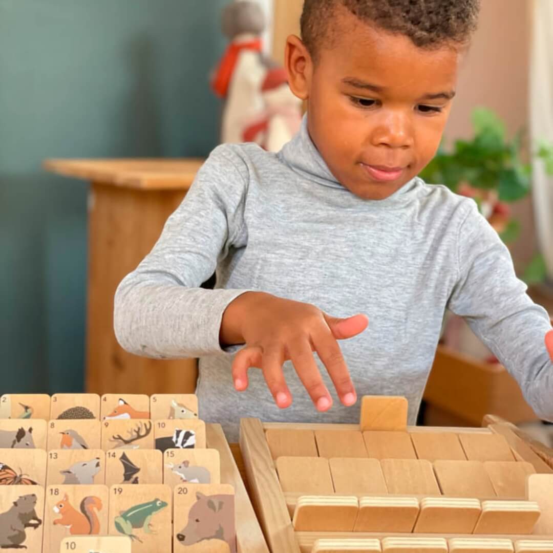 A young child playing the wooden Who Am I? guessing game by Egmont in a classroom setting. 