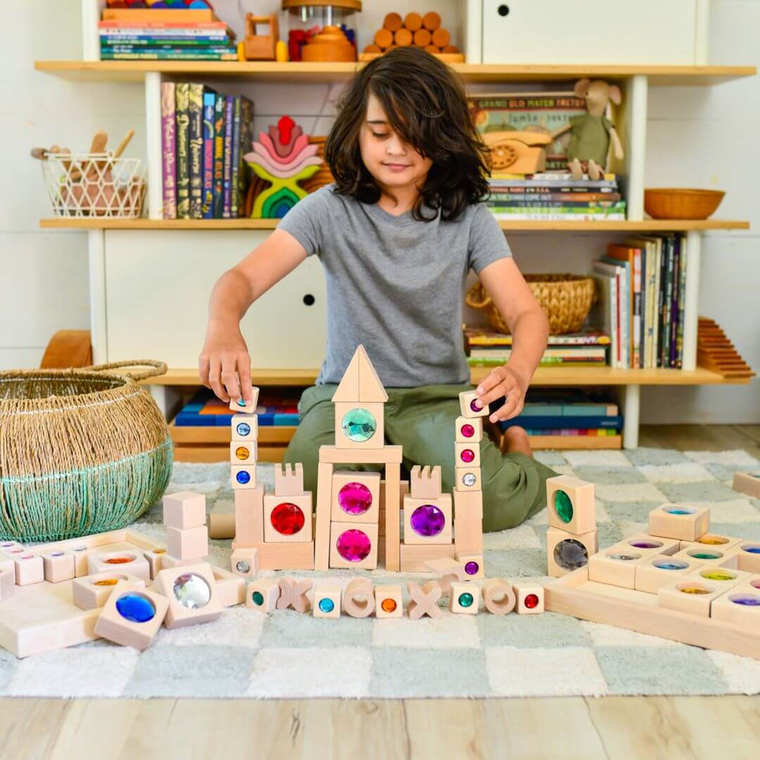 Child playing with wooden blocks in a room with shelves filled with books and toys.