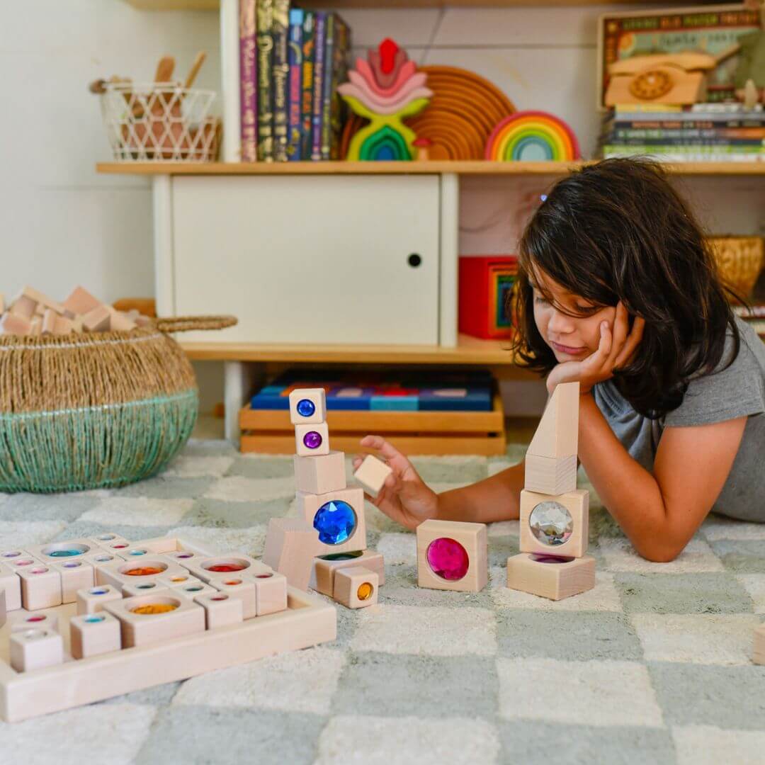 Child playing with wooden blocks in a room with shelves and toys.