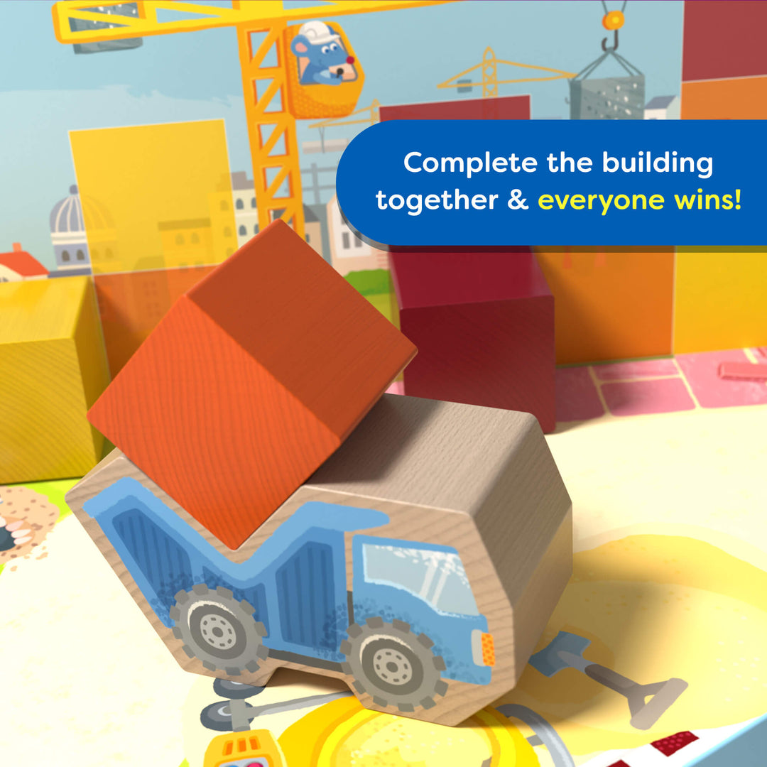Toy construction scene with a blue truck and colorful blocks from the game My Very First Games - Block by Block, featuring text 'Complete the building together & everyone wins!'.