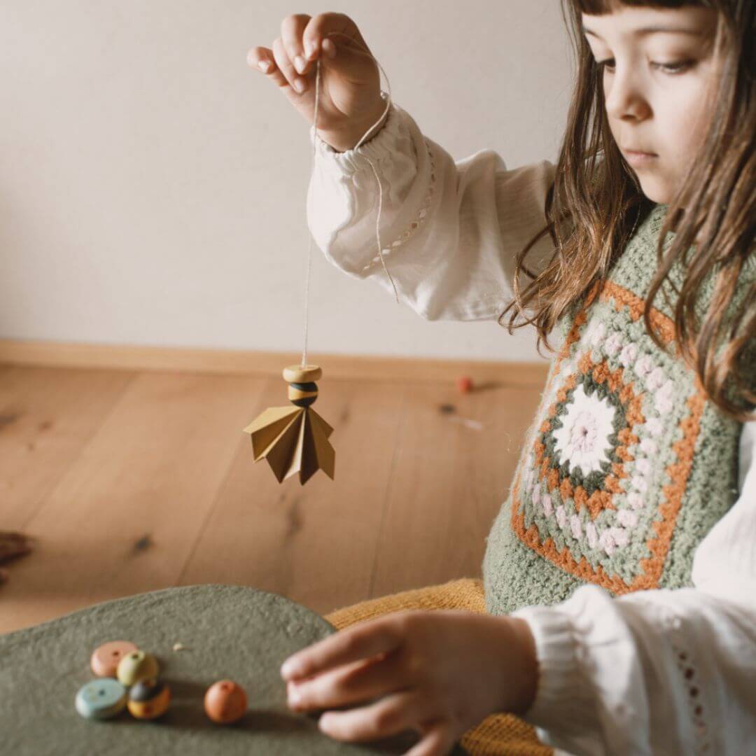 Child playing with wooden treasures from the Grapat 2025 Advent Calendar, holding a handcrafted hanging ornament – Bella Luna Toys.