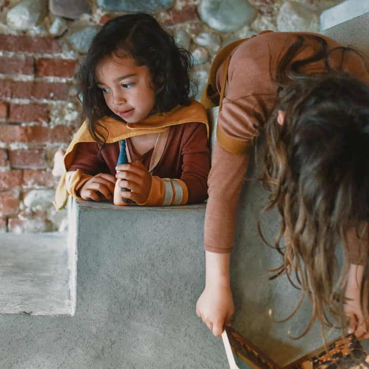 Two children exploring treasures from the Grapat 2025 Advent Calendar, one holding a wooden piece while the other leans over a step – Bella Luna Toys.