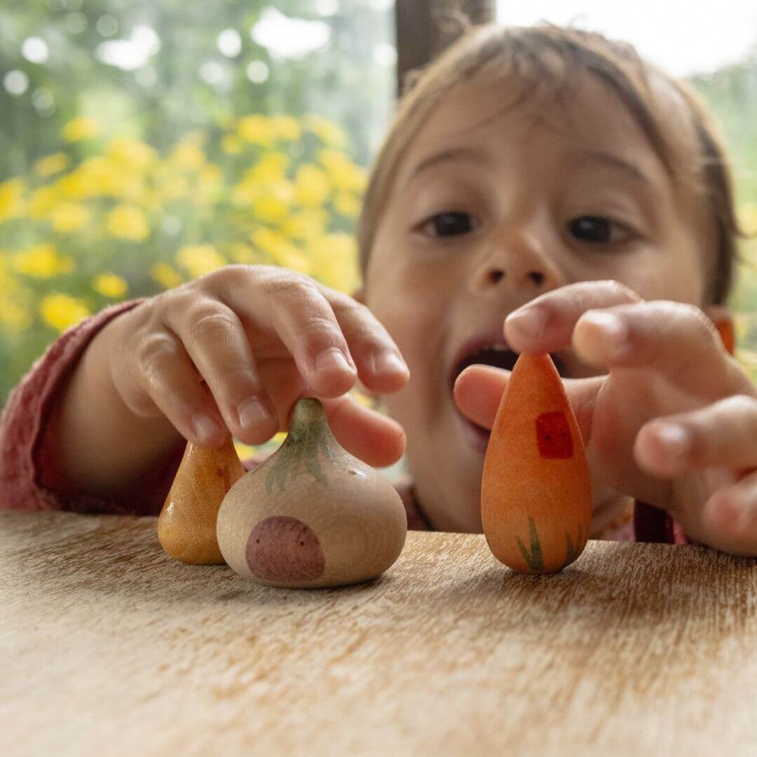 Child playing with wooden Grapat figures from the Lucky Lucky blind boxes, holding two vibrantly painted characters with a joyful expression.