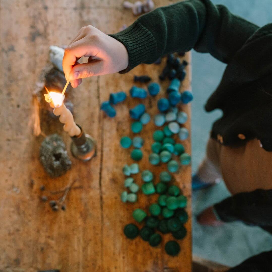 A child lighting a candle with the Grapat Mandala Mix Cold set arranged by color in the foreground - Bella Luna Toys
