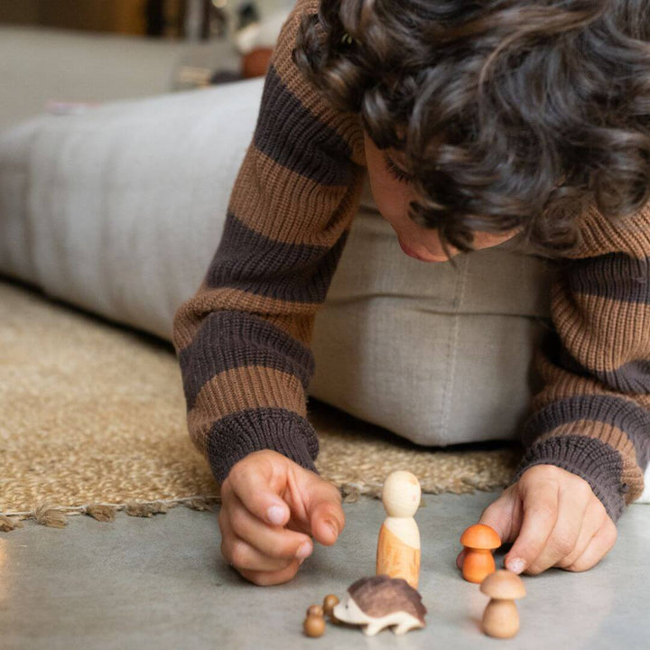 Child playing on the floor with the Grapat x Ostheimer Hello Autumn! wooden set, including figure, hedgehog, and mushrooms – Bella Luna Toys.