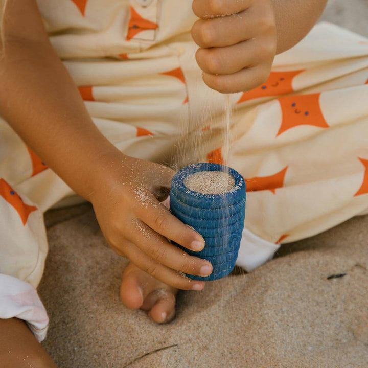 Child pouring sand into Grapat Pots blue vase