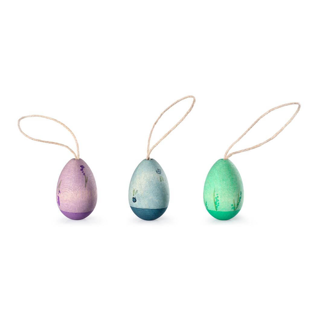 A set of three handcrafted wooden Easter egg ornaments from Grapat, arranged in a row against a white background. Each egg features cool, colors in shades of blue, green, and purple, with a natural wood texture and delicate painted details. Each ornament has a looped string for hanging, making them perfect for festive Easter decorations.