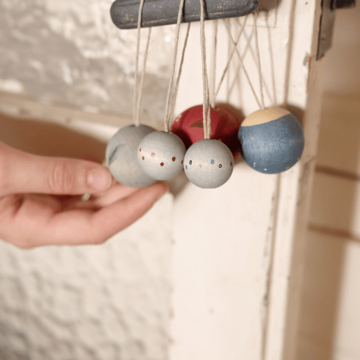 Hand holding a cluster of Grapat Wish Balls Wooden Ornaments hanging by their threads from a hook – Bella Luna Toys.