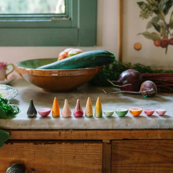 Grapat wooden vegetable play set with 12 hand-painted wooden veggies in assorted shapes and natural colors lined up on a kitchen counter - rBella Luna Toys