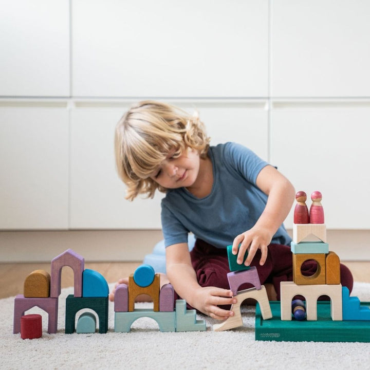 Child building with blocks from the Grimm's Wooden Toys Tiny Art Collection