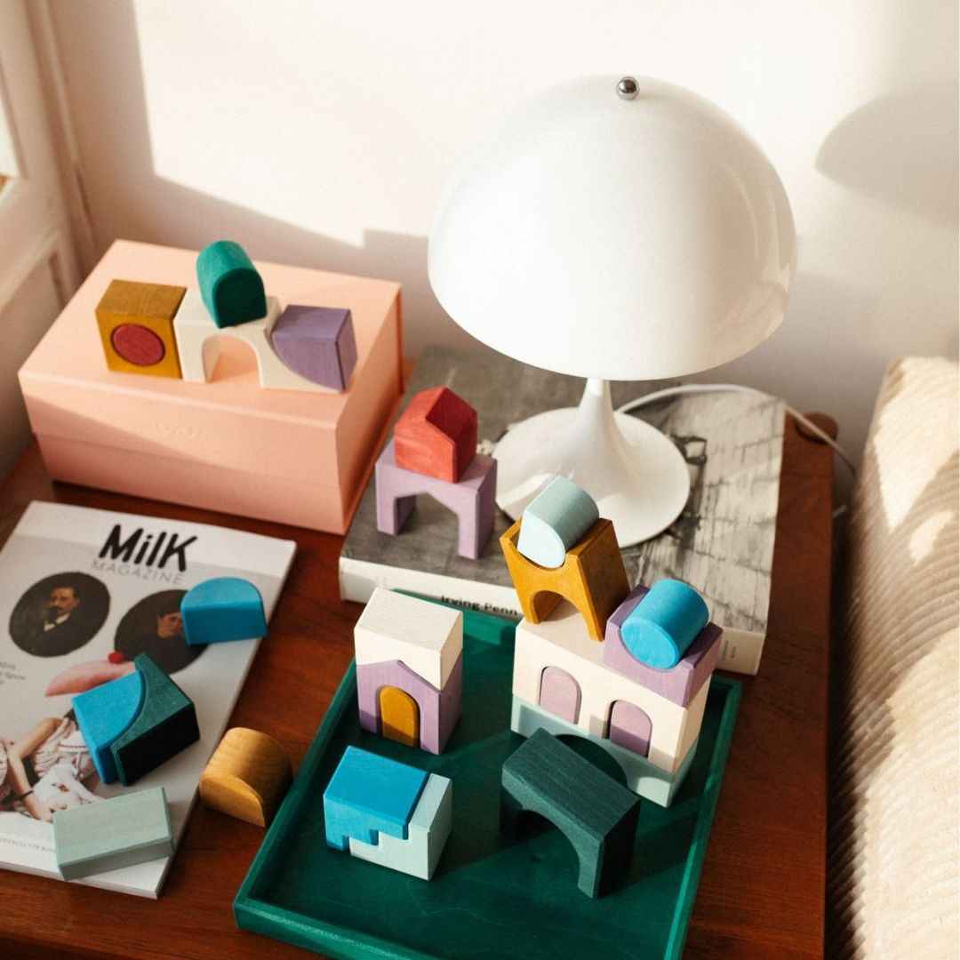 Blocks from the Grimm's Wooden Toys Tiny Art Collection on a table with lamp.