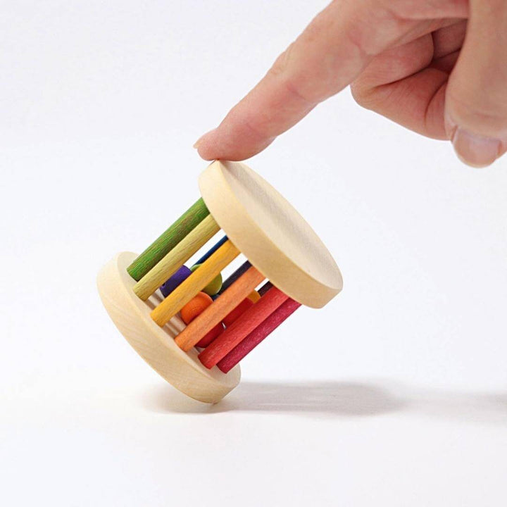An adult sized hand holding the Grimm's Spiel & Holz - Grimm's Mini Rolling Wheel - Bella Luna Toys