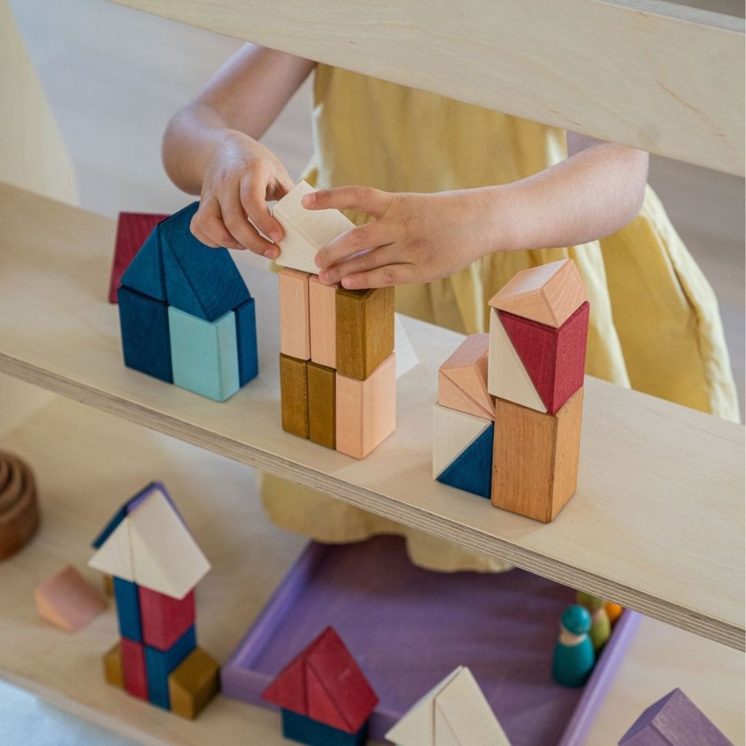 A child building with blocks from the Grimm's Wooden Toys Tiny Art Collection.