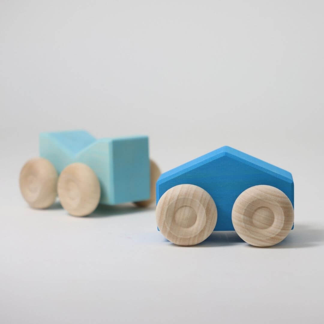 Two blue wooden stacking cars by Grimm’s, handcrafted with natural wood wheels and smooth, colorful bodies, perfect for open-ended building and rolling play  Bella Luna Toys 