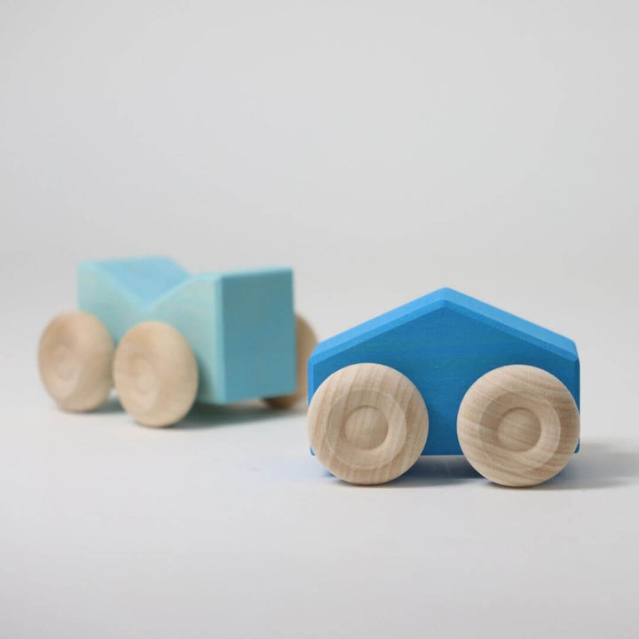 Two blue wooden stacking cars by Grimm’s, handcrafted with natural wood wheels and smooth, colorful bodies, perfect for open-ended building and rolling play  Bella Luna Toys 