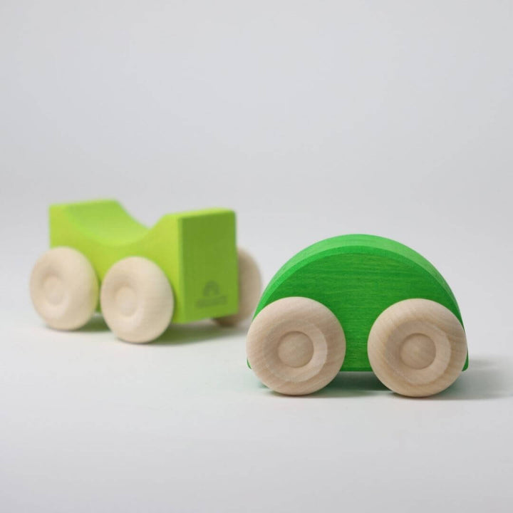 Two green wooden stacking cars by Grimm’s, handcrafted with natural wood wheels and smooth, colorful bodies for open-ended building and rolling play - Bella Luna Toys