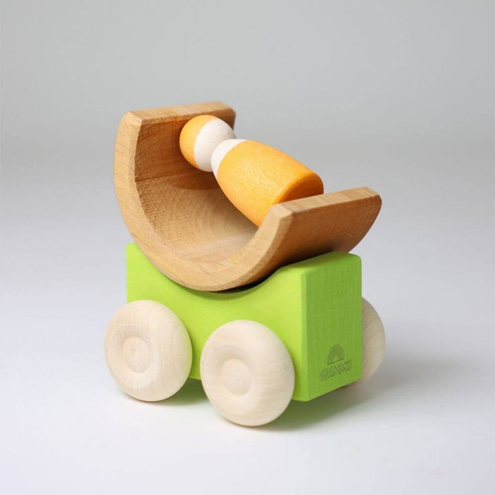 Green Grimm’s stacking car with natural wood wheels, topped with a curved wooden block and yellow piece—showing creative, open-ended building possibilities. Bella Luna Toys