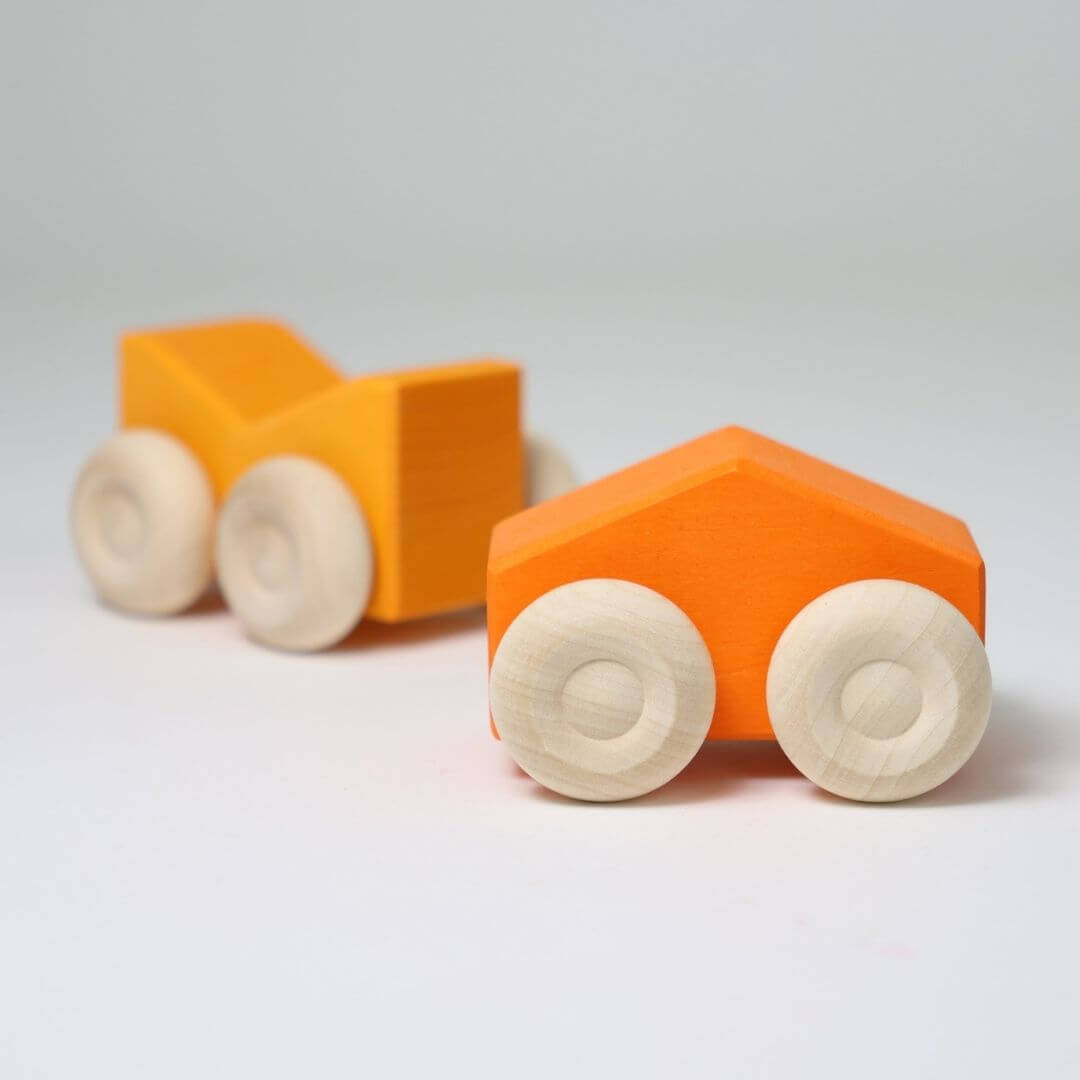 Two orange wooden stacking cars by Grimm’s, handcrafted with natural wood wheels and smooth, colorful bodiesfor open-ended building and rolling play - Bella Luna Toys