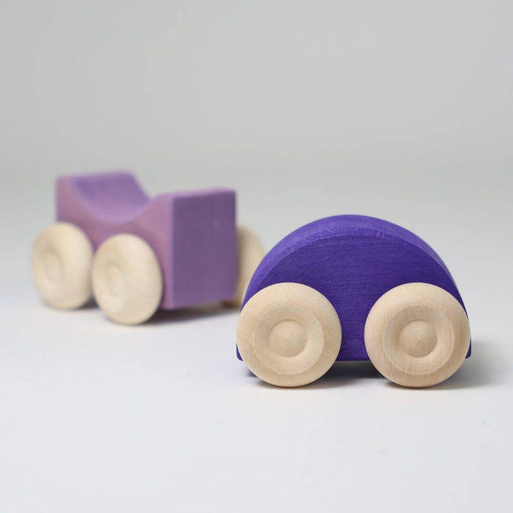Two purple wooden stacking cars by Grimm’s, handcrafted with natural wood wheels and smooth, colorful bodies for open-ended building and rolling play.