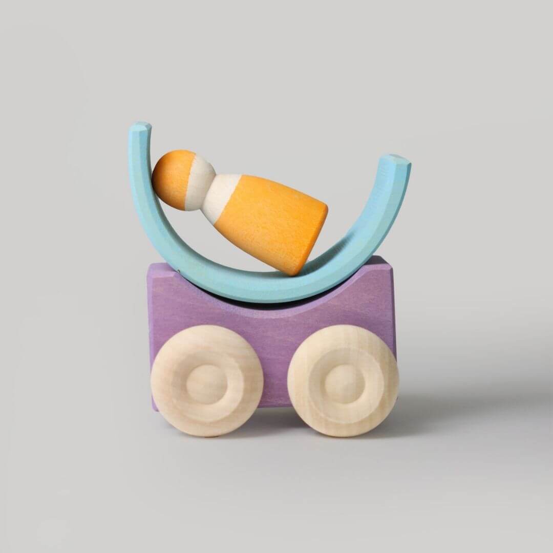 Purple Grimm’s stacking car with natural wood wheels, topped with a blue curved wooden block and orange nin figure—showing creative, open-ended building possibilities. Bella Luna Toys