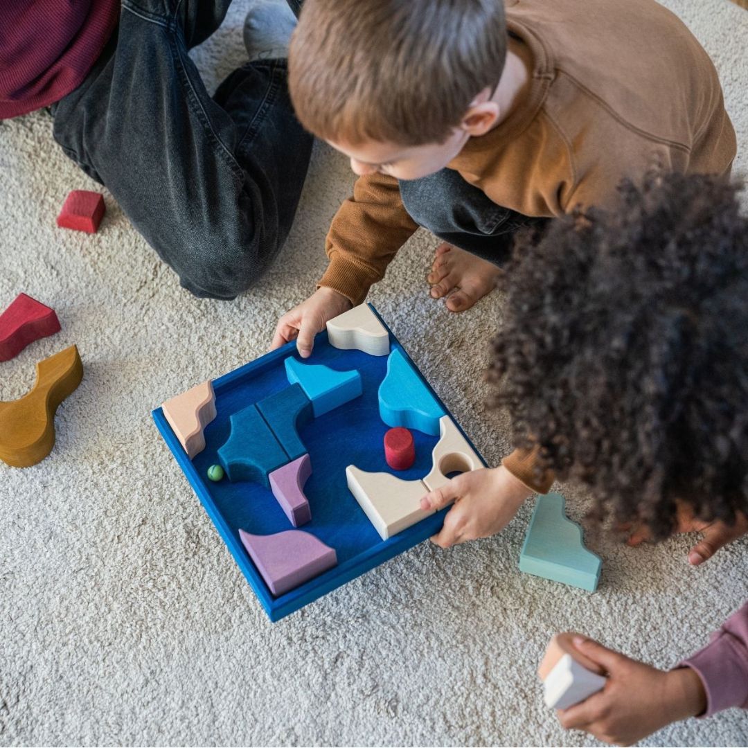 Children playing with a marble run made from the Grimm's Wooden Toys Tiny Art Collection.
