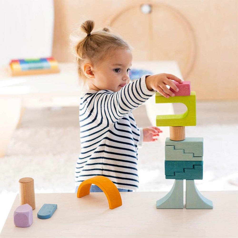 Child playing with Grimm's Wooden Building World Cloud Play Set