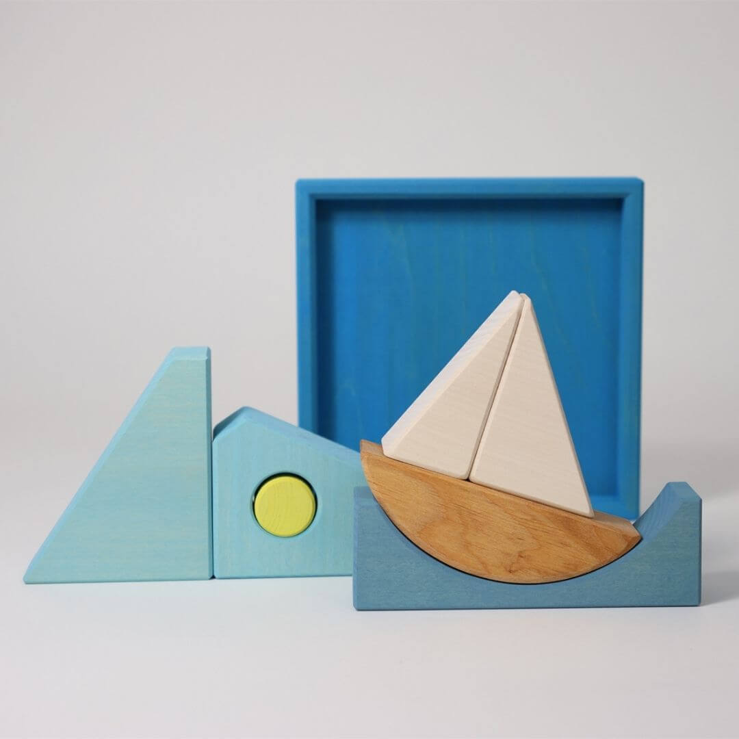 Grimm’s Wooden Puzzle and Building Set in blue shown with sailboat pieces arranged outside the tray, creating waves and sea-inspired shapes for imaginative play. Bella Luna Toys