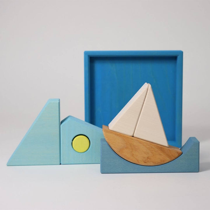 Grimm’s Wooden Puzzle and Building Set in blue shown with sailboat pieces arranged outside the tray, creating waves and sea-inspired shapes for imaginative play. Bella Luna Toys
