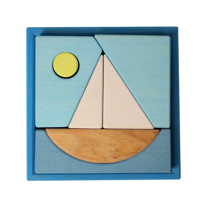 Grimm’s Wooden Puzzle and Building Set in blue, featuring a sailboat design with geometric shapes and a small yellow sun inside a square blue frame. Bella Luna Toys 