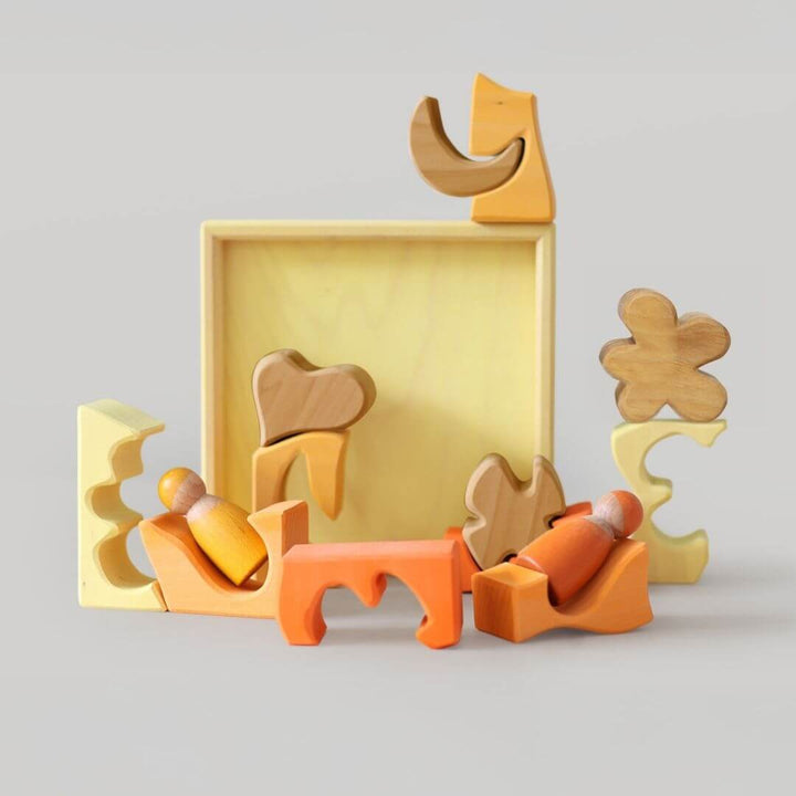 Grimm’s Wooden Puzzle and Building Set in yellow shown with organic-shaped pieces arranged outside the frame, forming playful sculptures and designs. Bella Luna Toys