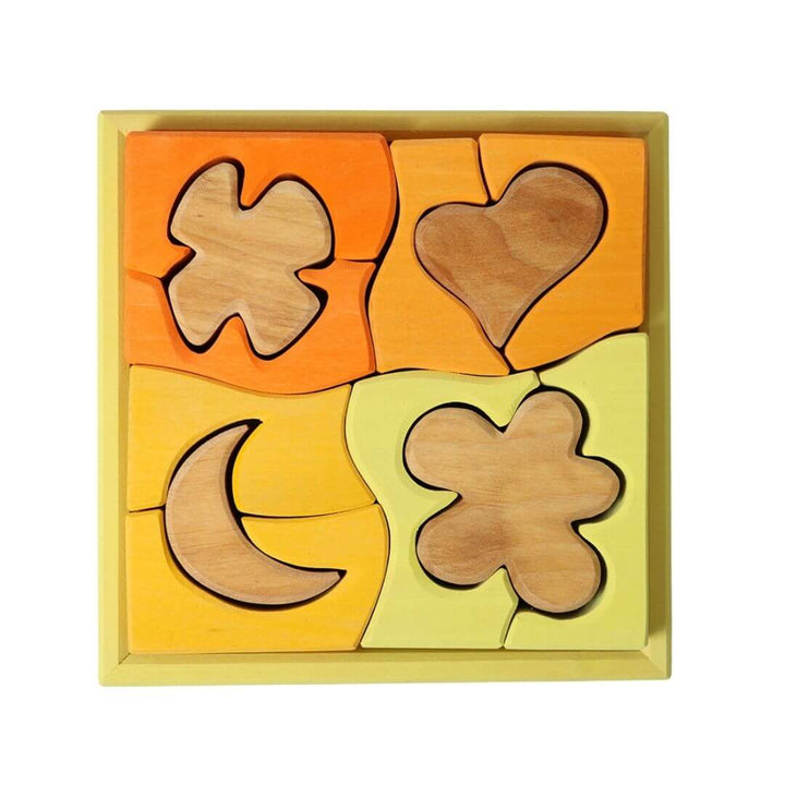 Grimm’s Wooden Puzzle and Building Set in yellow, featuring warm-toned shapes like hearts, moons, and clovers inside a square frame. Bella Luna Toys