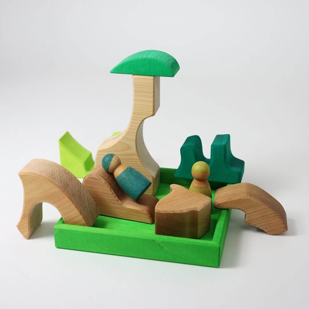 Grimm’s Wooden Puzzle and Building Set in green displayed with pieces arranged outside the frame, forming a woodland scene with trees and a squirrel figure. Bella Luna Toys