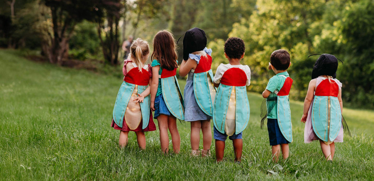 Kids standing in a line outside with firefly costumes.