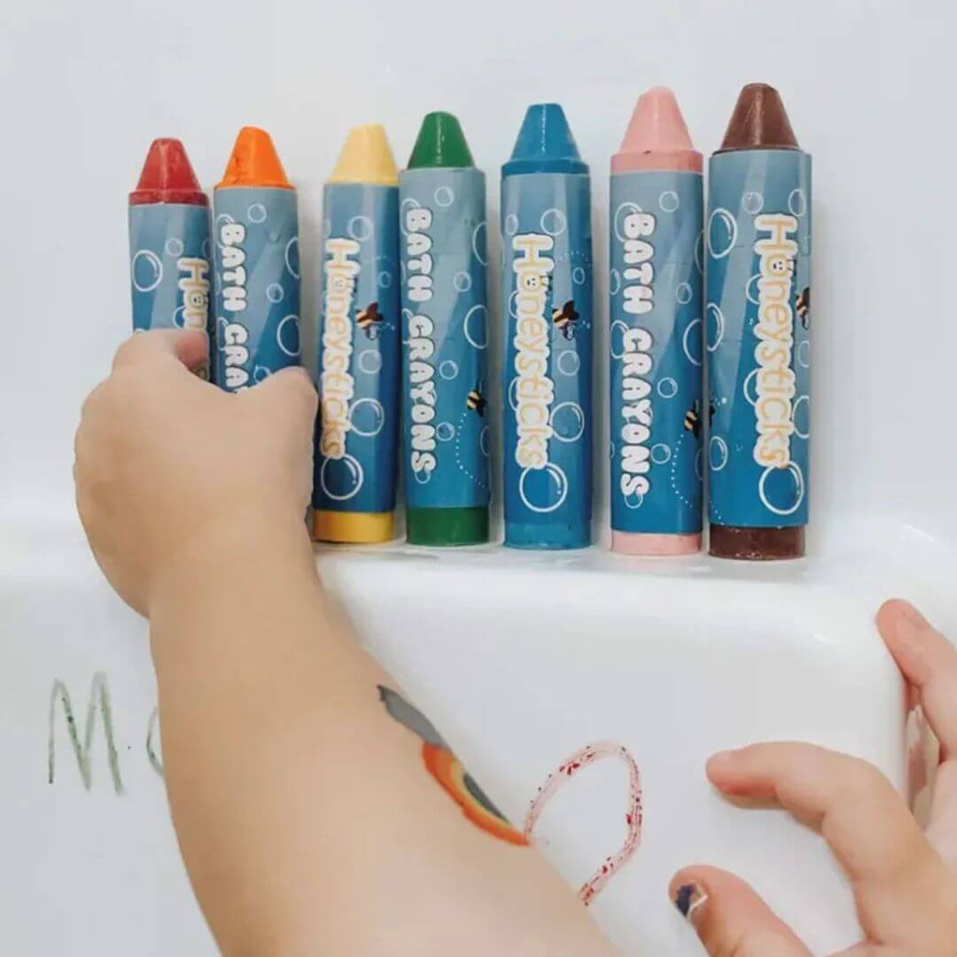 Set of jumbo beeswax bath crayons with a child's hand holding a white container.