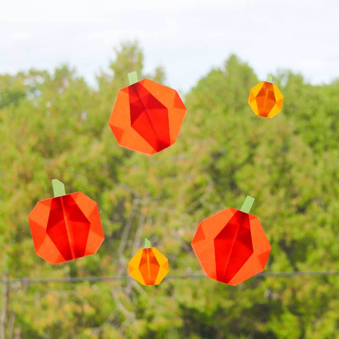 Geometric pumpkin decorations against a green tree background