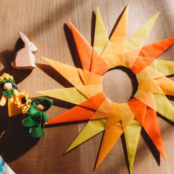 Decorative sun-shaped object with colorful rays on a wooden surface