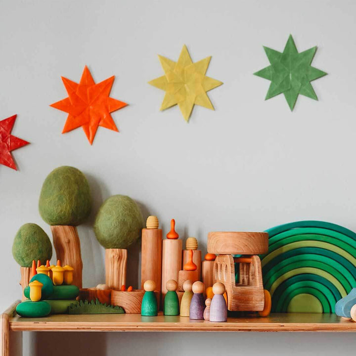 Colorful wooden toys and decorations on a shelf against a light gray wall with star-shaped decorations.