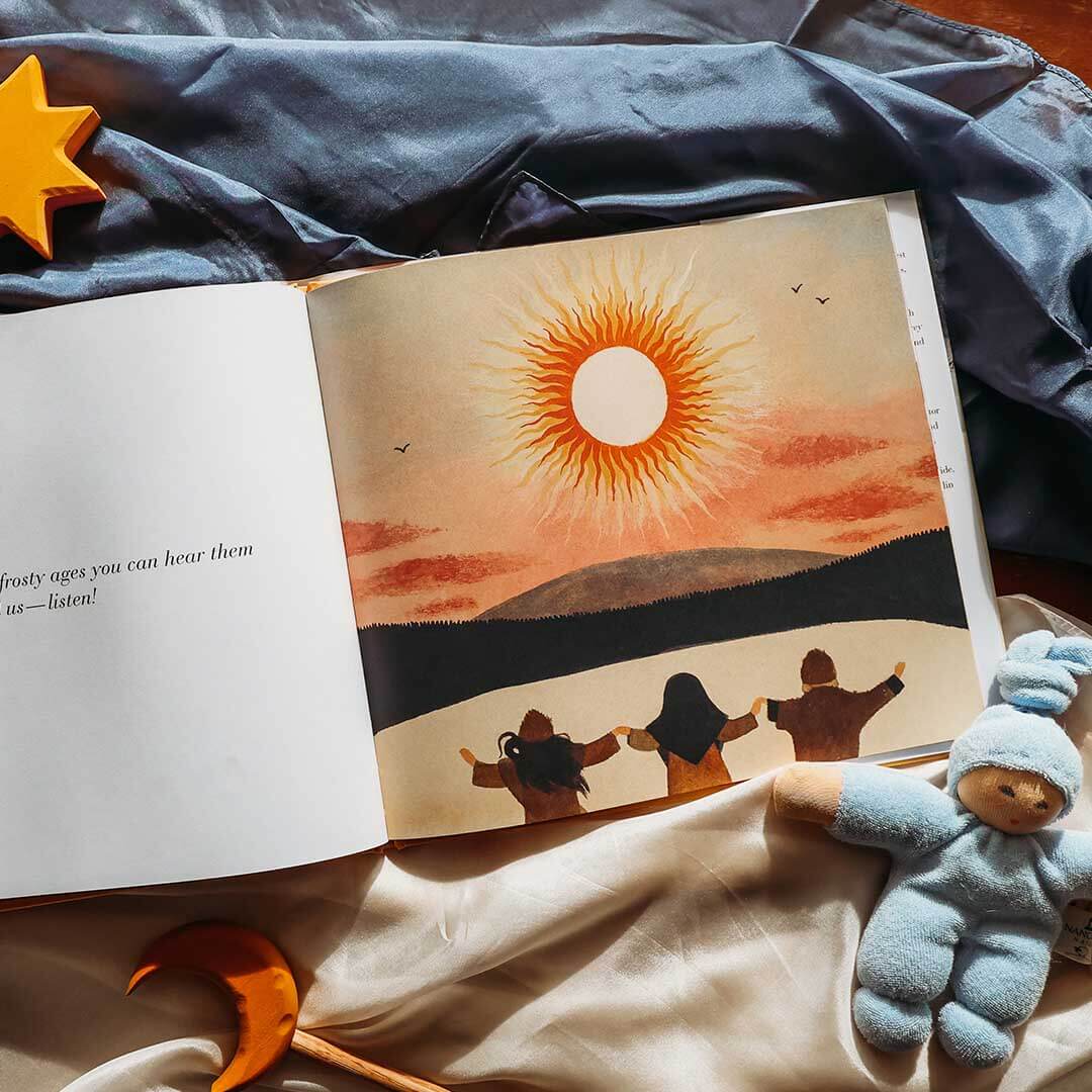 Open book with a sunset illustration on a bed with toys