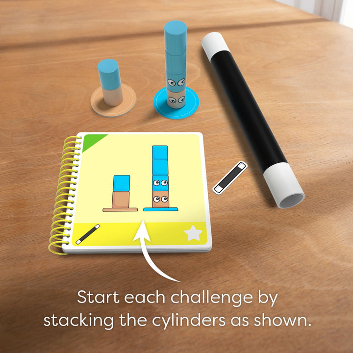 Tabletop with stacked cylinders, notebook, and a wand with the words "Start each challenge by stacking the cylinders as shown."