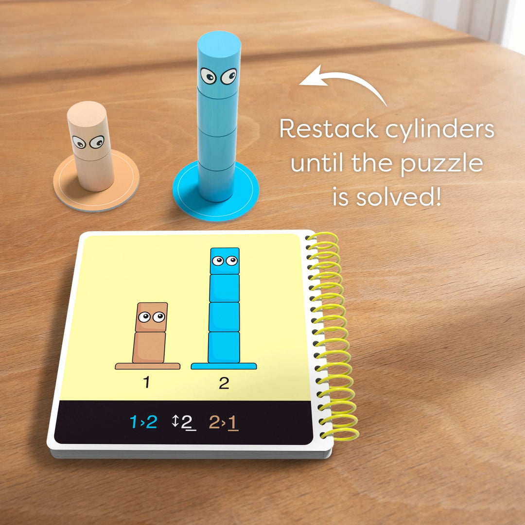 Two stacks of cylindrical pieces on a table, one tan and one blue, next to a puzzle booklet with instructions with the words 'Restack cylinders until the puzzle is solved!"
