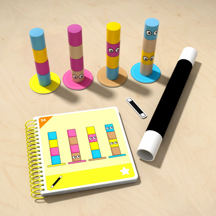 Colorful wooden block stacks with eyes, a yellow spiral-bound book showing similar stacks, and a black and white magic wand