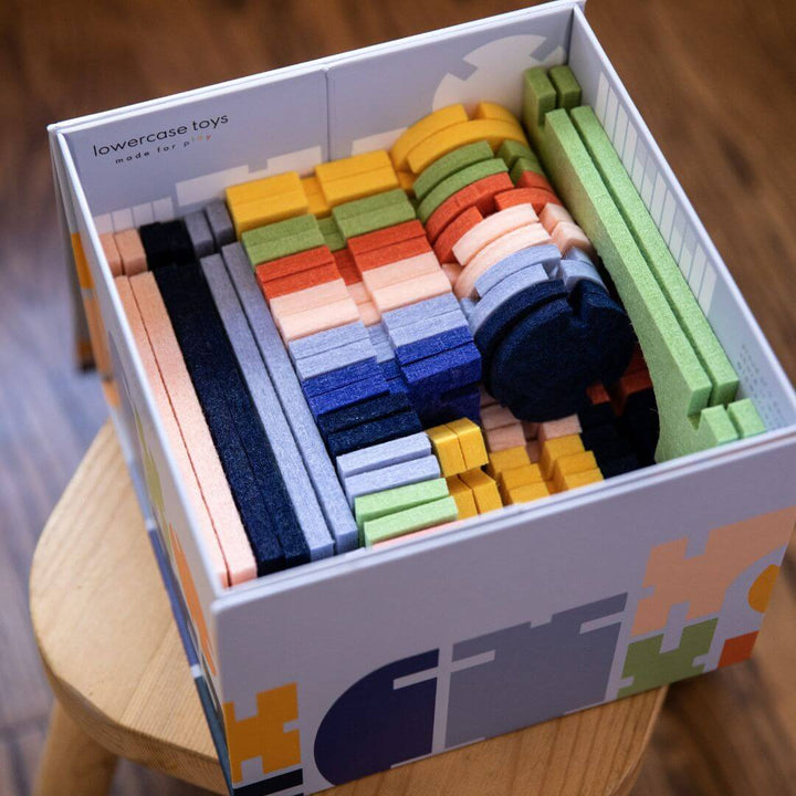 92-piece Architectural Felt Block Set with colorful interlocking recycled felt pieces, including blocks, arches, domes, and joiners, shown in the sturdy box they come in.