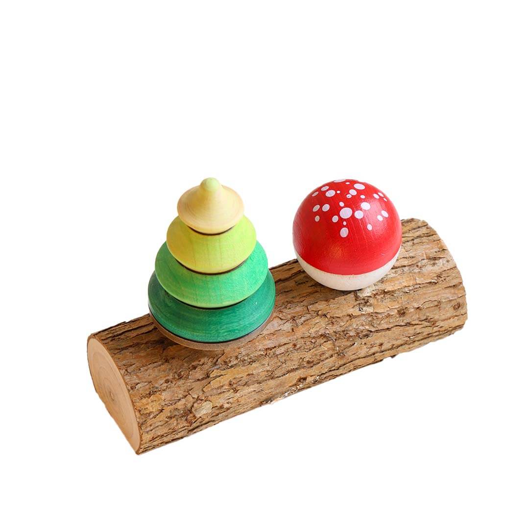 Wooden toy set with colorful rings and a red mushroom on a wooden log against a white background