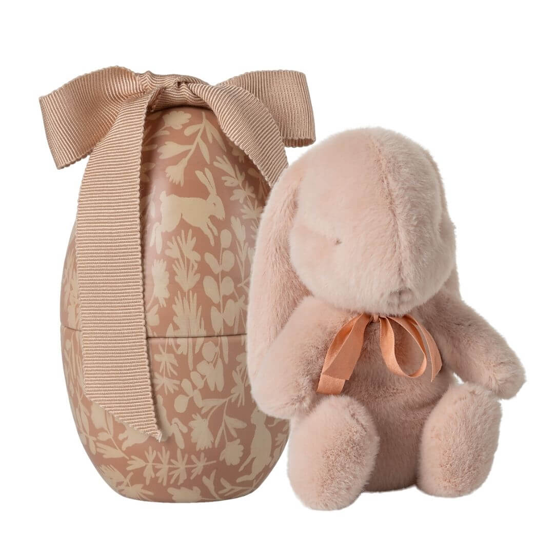 Maileg powder pink plush bunny with ribbon collar beside floral metal Easter egg with fabric bow