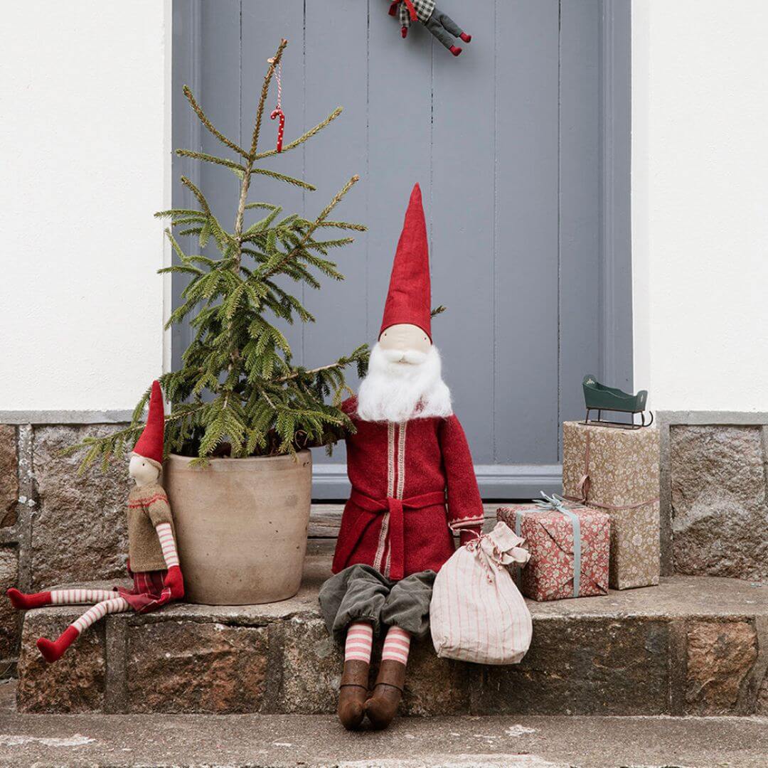 Maileg Large Santa displayed sitting outside near a Maileg pixie in a holiday setting with seasonal décor, highlighting his handcrafted clothes and tall, festive presence. Bella Luna Toys