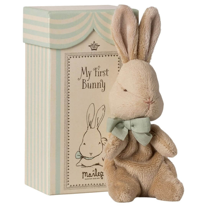 My First Bunny by Maileg in brown, a soft plush bunny with a ribbon bow, sitting beside its illustrated keepsake gift box.